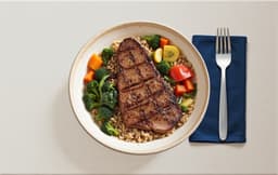 Pan-fried beef steak with brown rice, vegetables, and spinach
